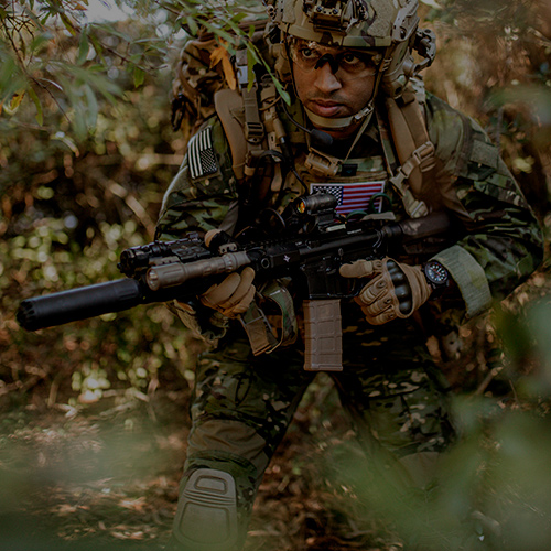 Active-Duty Mil: U.S. Military soldier carrying a rifle equipped with a red dot optic during training exercises. 